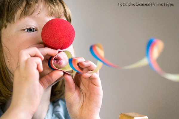 Karneval an der Grundschule Mädchen mit Clownsnase pustet eine Luftschlange