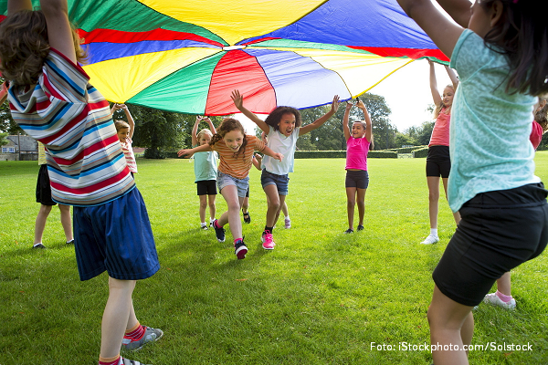 Grundschulkinder spielen mit einem bunten Schwungtuch