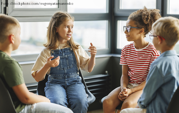 Sprachförderung in der Grundschule: Vier Kinder sitzen im Stuhlkreis und diskutieren.